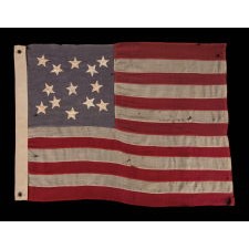 13 STAR FLAG WITH A MEDALLION CONFIGURATION OF HAND-SEWN STARS ON A DUSTY BLUE CANTON; A SMALL-SCALE ANTIQUE AMERICAN FLAG OF THE LATE 19TH CENTURY: