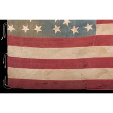 ANTIQUE AMERICAN FLAG OF THE CIVIL WAR PERIOD, WITH THE RARE PRESENCE OF A COPPERPLATE-PRINTED EAGLE IN THE CANTON, SET WITHIN A FRACTURED WREATH PATTERN OF 34 STARS AND WITH ITS CANTON RESTING ON THE WAR STRIPE; REFLECTS THE PERIOD OF KANSAS STATEHOOD, 1861-63