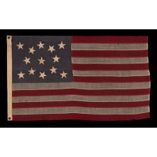 13 STAR ANTIQUE AMERICAN FLAG, WITH A MEDALLION CONFIGURATION OF HAND-SEWN STARS ON A DUSTY BLUE CANTON, A SMALL-SCALE EXAMPLE OF THE LATE 19TH CENTURY