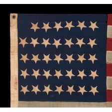 34 UPSIDE-DOWN, HAND-SEWN STARS IN A NOTCHED CONFIGURATION, ON AN ANTIQUE AMERICAN FLAG OF THE CIVIL WAR PERIOD, WITH A BEAUTIFUL AND HIGHLY UNUSUAL JACQUARD WEAVE BINDING, AND IN A TINY SCALE AMONG ITS COUNTERPARTS, REFLECTS THE ADDITION OF KANSAS AS THE 34TH STATE, 1861-1863
