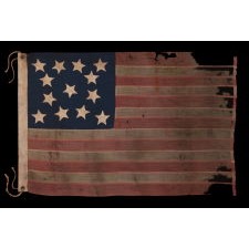13 STAR ANTIQUE AMERICAN FLAG WITH A MEDALLION CONFIGURATION OF HAND-SEWN STARS AND EXCEPTIONALLY ENDEARING GRAPHIC QUALITIES FROM HAVING BEEN EXTENSIVELY FLOWN; A SMALL SCALE EXAMPLE, MADE IN THE ERA OF THE 1876 CENTENNIAL OF AMERICAN INDEPENDENCE