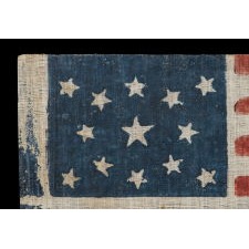 13 STAR ANTIQUE AMERICAN PARADE FLAG WITH A MEDALLION CONFIGURATION, MADE FOR THE 1876 CENTENNIAL OF AMERICAN INDEPENDENCE; A LARGE EXAMPLE AMONG ITS COUNTERPARTS OF THE PERIOD; PRESENTED IN THE FIRST EVER LARGE SCALE MUSEUM EXHBITION OF EARLY 13 STAR FLAGS