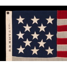 13 STAR ANTIQUE AMERICAN FLAG WITH A 3-2-3-2-3 CONFIGURATION OF STARS; A SMALL-SCALE EXAMPLE, MADE CIRCA 1895-1926, WITH AN OWNERSHIP STENCIL OF R.H. MACY & CO. ALONG THE HOIST