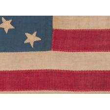 16 STARS IN A RARE AND BEAUTIFUL STARBURST MEDALLION THAT FEATURES A DISTINCT SALTIRE; A HOMEMADE AND ENTIRELY HAND-SEWN, ANTIQUE AMERICAN FLAG, MADE WITH AN ABOLITIONIST MESSAGE BY REMOVING THE SLAVE STATES FROM THE STAR COUNT, circa 1850-1858, YET WITH A COMBINATION OF TRAITS AND FEATURES THAT CURIOUSLY REFLECT TENNESSEE AS THE 16TH STATE TO JOIN THE UNION AND THE 11TH STATE TO LEAVE