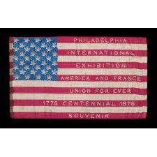 EXTRAORDINARY SILK FLAG MADE FOR THE 1876 CENTENNIAL INTERNATIONAL EXPOSITION IN PHILADELPHIA, WITH WOVEN TEXT ON EITHER SIDE, PROBABLY MADE AT ONE OF THE FRENCH EXHIBITS AT THE FAIR AND SOLD AS A SOUVENIR