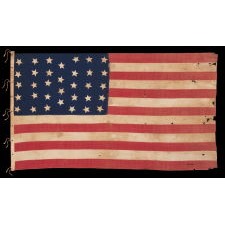 34 STAR ANTIQUE AMERICAN FLAG, HOMEMADE AND WITH HAND-SEWN STARS, ARRANGED IN AN UNUSUAL LINEAL PATTERN THAT HAS A SINGLE COLUMN OF 4 STARS BETWEEN COLUMNS OF 5; OPENING TWO YEARS OF THE CIVIL WAR, 1861-1863, LIKELY FIELD CARRIED, REFLECTS KANSAS STATEHOOD