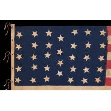 34 STAR ANTIQUE AMERICAN FLAG, HOMEMADE AND WITH HAND-SEWN STARS, ARRANGED IN AN UNUSUAL LINEAL PATTERN THAT HAS A SINGLE COLUMN OF 4 STARS BETWEEN COLUMNS OF 5; OPENING TWO YEARS OF THE CIVIL WAR, 1861-1863, LIKELY FIELD CARRIED, REFLECTS KANSAS STATEHOOD