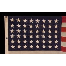 ANTIQUE AMERICAN FLAG WITH 48 STARS, A U.S. NAVY SMALL BOAT ENSIGN, MADE IN JUNE OF 1943, DURING WWII, AT MARE ISLAND, CALIFORNIA, HEADQUARTERS OF THE PACIFIC FLEET, WITH ENDEARING WEAR FROM OBVIOUS LONG-TERM USE