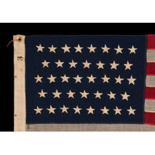 38 HAND-SEWN STARS ON AN ANTIQUE AMERICAN FLAG IN AN EXTRAORDINARILY TINY SCALE AMONG ITS PIECED-AND-SEWN COUNTERPARTS, MADE AT THE TIME WHEN COLORADO WAS THE MOST RECENT STATE TO JOIN THE UNION, 1876-1889; PROBABLY MADE BY THE ANNIN COMPANY IN NEW YORK CITY, SIGNED BY MEMBERS OF THE GRIMES & JOHNSON FAMILIES OF CANANDAIGUA, NEW YORK