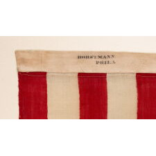 38 CANTED STARS IN STAGGERED ROWS, ON A CLAMP-DYED, WOOL, ANTIQUE AMERICAN FLAG MADE BY THE HORSTMANN BROTHERS IN PHILADELPHIA, ALMOST CERTAINLY FOR DISPLAY AT THE 1876 CENTENNIAL EXPOSITION; A VERY RARE EXAMPLE WITH STRONG COLORS AND GREAT TEXTURE; REFLECTS COLORADO STATEHOOD
