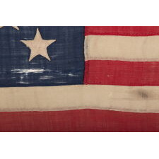 ENTIRELY HAND-SEWN ANTIQUE AMERICAN FLAG OF THE CIVIL WAR ERA, WITH 13 SINGLE-APPLIQUÉD STARS IN A 3-2-3-2-3 CONFIGURATION, IN A GREAT, SMALL SCALE AMONG ITS COUNTERPARTS, PROBABLY MADE IN NEW YORK CITY, SIGNED “GRÜNFILD”