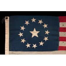 13 STAR ANTIQUE AMERICAN FLAG, WITH A CIRCULAR ARRANGEMENT OF WHAT IS KNOWN AS THE 3RD MARYLAND PATTERN, ON A SMALL SCALE EXAMPLE WITH BEAUTIFUL, ELONGATED PROPORTIONS AND AN UNUSUALLY LARGE CENTER STAR, MADE CIRCA 1890-1900