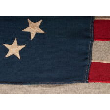 13 STAR ANTIQUE AMERICAN FLAG, WITH A CIRCULAR ARRANGEMENT OF WHAT IS KNOWN AS THE 3RD MARYLAND PATTERN, ON A SMALL SCALE EXAMPLE WITH BEAUTIFUL, ELONGATED PROPORTIONS AND AN UNUSUALLY LARGE CENTER STAR, MADE CIRCA 1890-1900