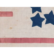 31 STARS IN A GREAT STAR PATTERN, ON AN ANTIQUE AMERICAN FLAG MADE DURING THE PERIOD OF CALIFORNIA STATEHOOD (1850-1858), WITH APPLIQUÉD TEXT ADDED TO CELEBRATE INDEPENDENCE DAY, 1858, THE PRECISE DAY THAT A 32nd STAR WAS OFFICIALLY ADDED FOR MINNESOTA; A MAKE-DO EXAMPLE WITH RIBBON AS STRIPES & EXCEPTIONAL FOLK QUALITIES, CLOSELY RELATED TO FLAGS FOUND IN THE FORMER MAINE HOME OF CPL. JOHN WILLIAM MORIN, WHO FOUGHT WITH THE 20th MAINE REGIMENT UNDER COL. JOSHUA CHAMBERLIN AT GETTYSBURG
