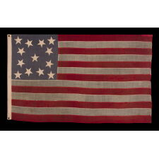 13 STAR ANTIQUE AMERICAN FLAG WITH A DUSTY BLUE CANTON, MADE IN THE ERA OF THE 1876 CENTENNIAL, IN AN INTERESTING CONFIGURATION THAT FEATURES TRIOS OF STARS IN EACH CORNER AND A SINGLE, CENTER STAR; A RARE VARIANT THAT I CLASSIFY “TRI-CORNER HAT” MEDALLION