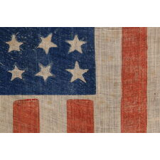 36 STAR ANTIQUE AMERICAN PARADE FLAG, WITH STARS THAT ALTERNATE IN THEIR VERTICAL POSITION FROM COLUMN TO COLUMN AND ROW-TO-ROW, PRINTED ON AN ESPECIALLY INTERESTING LENGTH OF COARSE COTTON WITH A CRUDE WEAVE THAT RESULTS IN A VISUALLY COMPELLING APPEARANCE; CIVIL WAR ERA, NEVADA STATEHOOD, 1864-1867