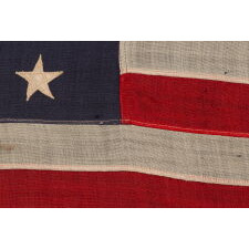 13 STAR ANTIQUE AMERICAN FLAG WITH A 3-2-3-2-3 CONFIGURATION OF STARS; A SMALL-SCALE EXAMPLE, MADE CIRCA 1895-1926, INSCRIBED “RoBT SCOTT” ALONG THE HOIST WITH A DIP PEN, SEEMINGLY BY A CHILD