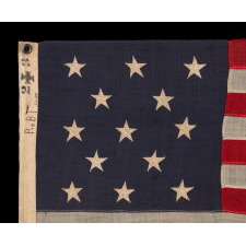 13 STAR ANTIQUE AMERICAN FLAG WITH A 3-2-3-2-3 CONFIGURATION OF STARS; A SMALL-SCALE EXAMPLE, MADE CIRCA 1895-1926, INSCRIBED “RoBT SCOTT” ALONG THE HOIST WITH A DIP PEN, SEEMINGLY BY A CHILD