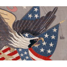 SAILOR’S SOUVENIR EMBROIDERY FROM THE WITH A FLYING, WARLIKE EAGLE SUPERIMPOSED ON A CANTED FEDERAL SHIELD & CROSSED AMERICAN FLAGS, BENEATH A STREAMER WITH THE LATIN MOTTO “E PLURIBUS UNUM,” INTERSPERSED WITH 13 STARS, circa 1890-1910