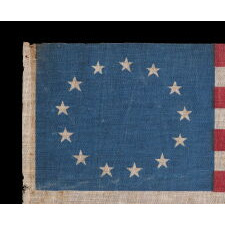 13 STAR ANTIQUE AMERICAN PARADE FLAG WITH A SINGLE WREATH OF STARS REMINISCENT OF THE BETSY ROSS PATTERN, BUT RENDERED AS MORE OF AN OVAL, THE ONLY EXAMPLE OF THIS EXACT VARIETY THAT I HAVE EVER ENCOUNTERED, MADE circa 1890-WWI (U.S. INVOLVEMENT 1917-18)