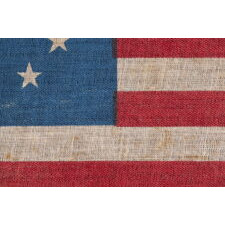 13 STAR ANTIQUE AMERICAN PARADE FLAG WITH A SINGLE WREATH OF STARS REMINISCENT OF THE BETSY ROSS PATTERN, BUT RENDERED AS MORE OF AN OVAL, THE ONLY EXAMPLE OF THIS EXACT VARIETY THAT I HAVE EVER ENCOUNTERED, MADE circa 1890-WWI (U.S. INVOLVEMENT 1917-18)