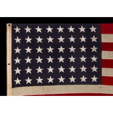 ANTIQUE AMERICAN FLAG WITH 48 STARS, A U.S. NAVY SMALL BOAT ENSIGN, MADE IN JANUARY OF 1944, DURING WWII (U.S. INVOLVEMENT 1941-45), AT MARE ISLAND, CALIFORNIA, FORMER HEADQUARTERS OF THE PACIFIC FLEET, WITH ENDEARING WEAR FROM LONG-TERM USE