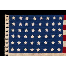 48 STARS ON A CROCHETED AMERICAN FLAG, PROBABLY MADE IN THE PATRIOTISM OF WWII (U.S. INVOLVEMENT 1941-1945), A BEAUTIFUL EXAMPLE WITH STRIKING COLORS, LARGER THAN TYPICAL IN SCALE, WITH AN INTERESTING, REPEATING, OPEN PATTERN ALONG THE HOIST, THROUGH WHICH A STAFF COULD BE THREADED